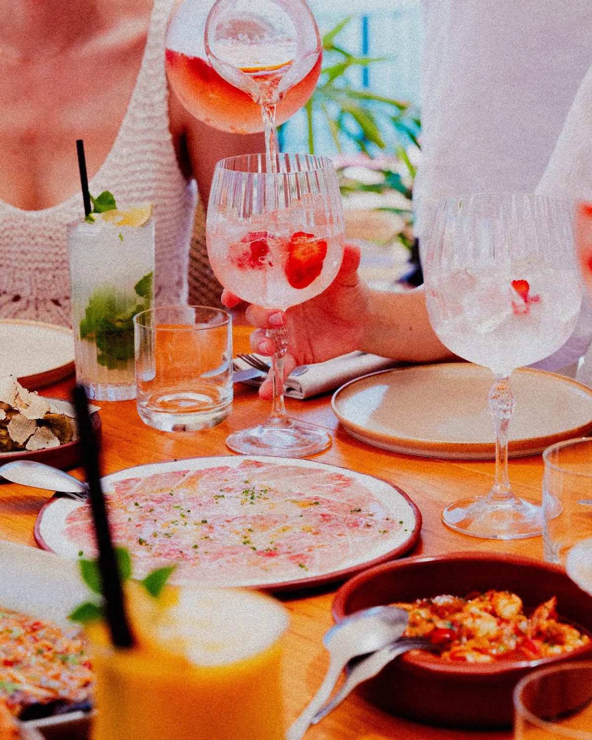 Mesa con copas de sangría, carpaccio y tapas mientras se sirve una jarra